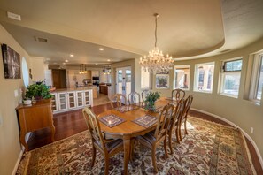 A spacious dining area with a large wooden table, chairs, and a chandelier. - Sorelle Vineyard ~ Spectacular Estate (Cornville)
