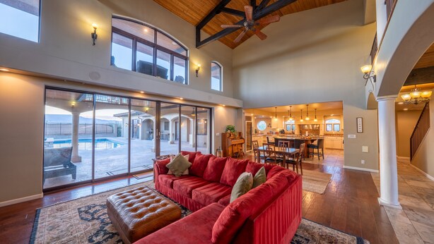 A spacious living area with a red sofa, a wooden ceiling, and a view of the outdoors.