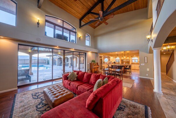A spacious living area with a red sofa, a wooden ceiling, and a view of the outdoors.