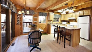 A wooden cabin with a kitchen featuring a central island, a dining area with a table and chairs, and a cozy seating area with a chair. - AWESOME VIEW! 1 bedroom, sleeps 2! (Sevierville)