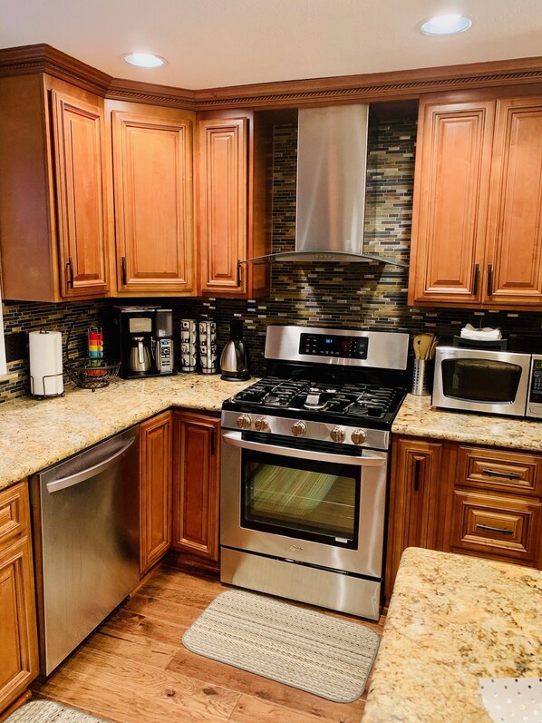 A kitchen with wooden cabinets, a stainless steel stove, a microwave, and a coffee maker.