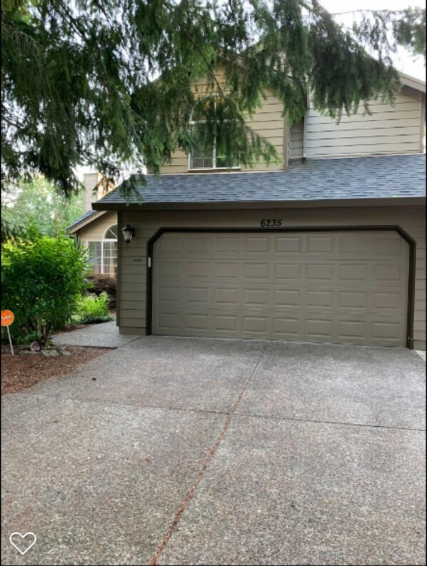 A residential garage with a number 6235 on the door, surrounded by trees and a driveway. - Cozy 3BR Home in Beaverton - Near Nike - Pet-Friendly (Beaverton)