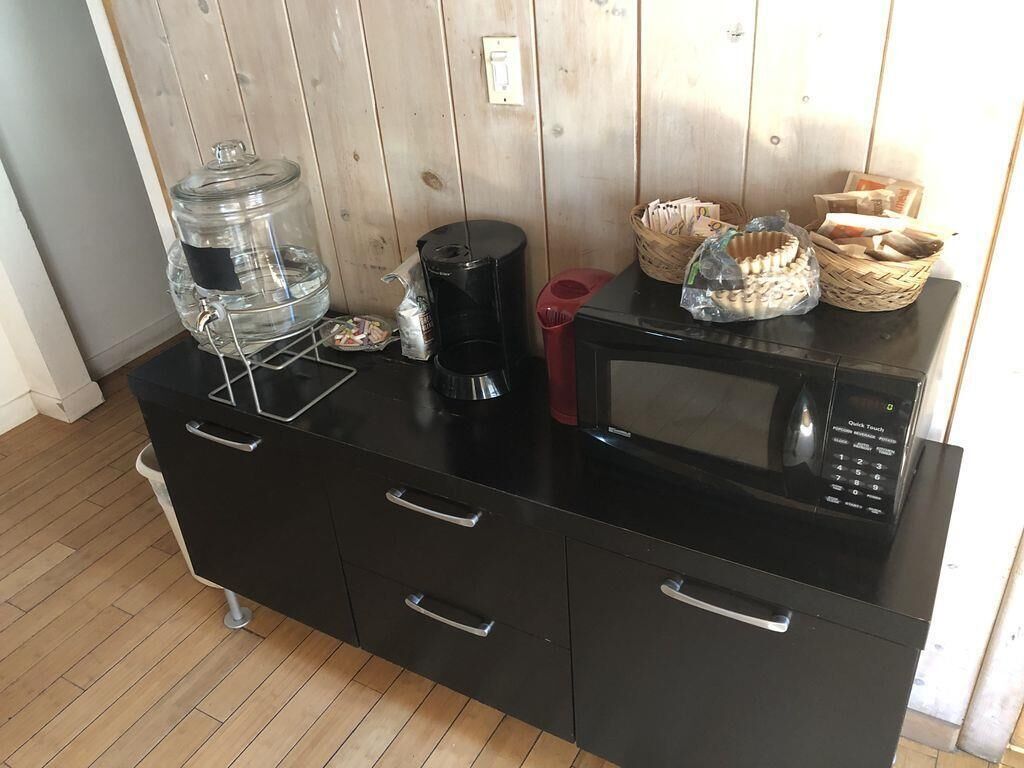 Une petite cuisine équipée d’un distributeur d’eau, d’une machine à café, d’un four à micro-ondes et de paniers de pain.