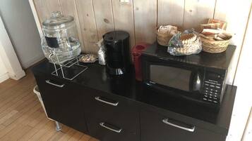 Une petite cuisine équipée d’un distributeur d’eau, d’une machine à café, d’un four à micro-ondes et de paniers de pain.