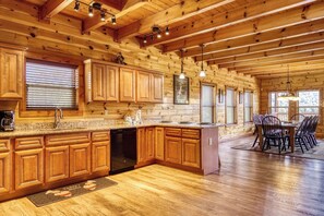 A spacious kitchen with wooden cabinets, granite countertops, and a dining area with a table and chairs.
