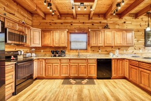 Une cuisine de style rustique, avec des murs en bois, un comptoir en granit, des appareils en acier inoxydable et des armoires en bois.