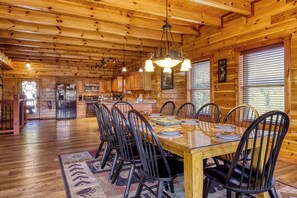 L’intérieur d’un chalet en bois comprend un coin repas, une cuisine et une grande fenêtre.