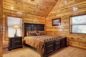 A wooden-paneled bedroom with a bed, nightstands, and a framed picture on the wall.