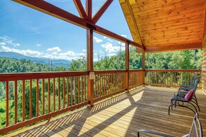 Una terraza de madera con vistas a un bosque y montañas.