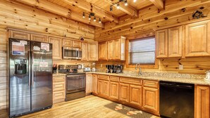 A modern kitchen with wooden cabinets, stainless steel appliances, and a granite countertop. - Luxury 5BR Cabin w/ Private Pool, Firepit, Theater & Game Room – In Gatlinburg (Gatlinburg)
