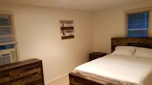 Un dormitorio con una cama de madera, una mesita de noche, un aparador y una obra de arte en la pared.