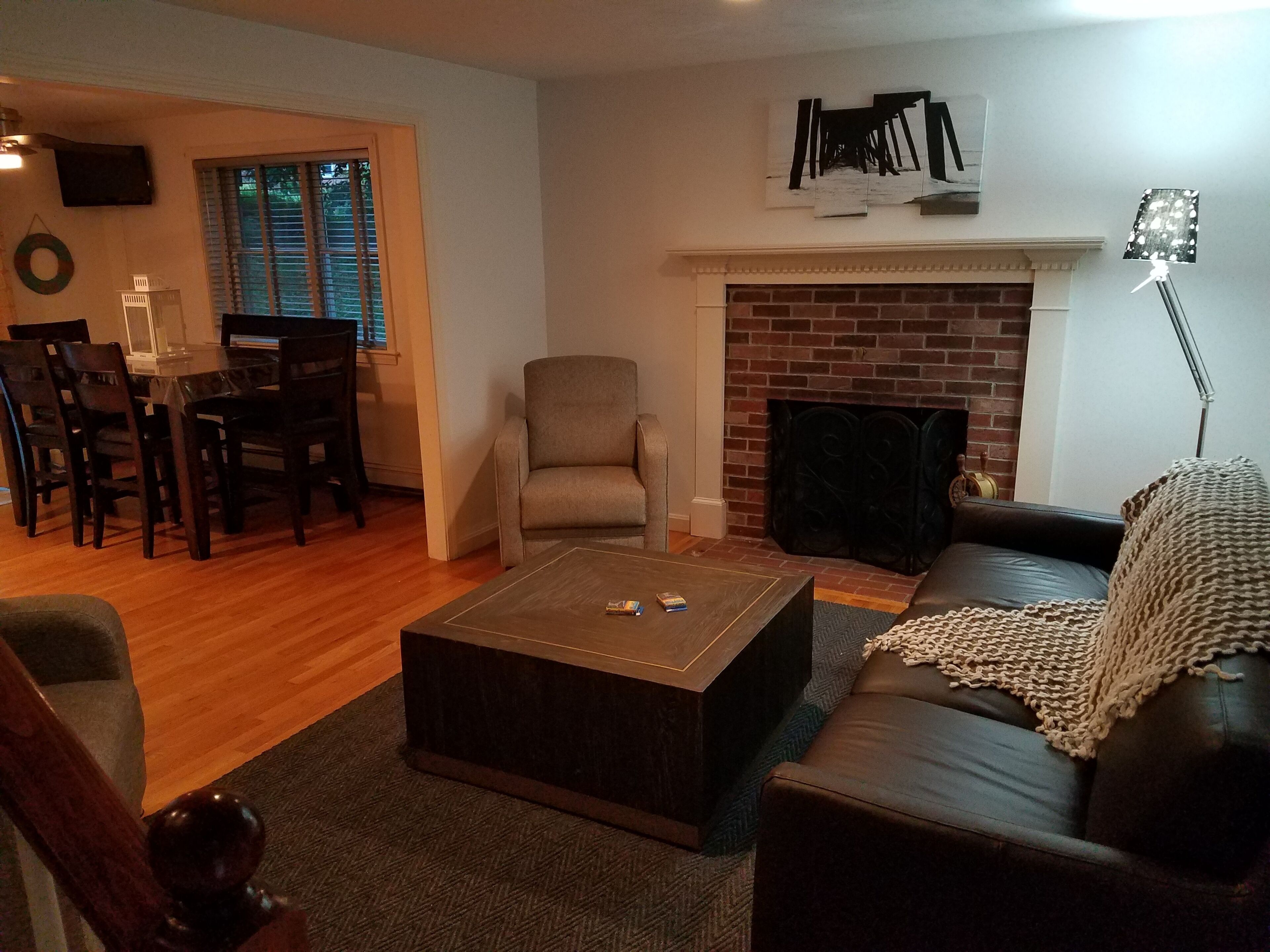 Een woonkamer met een open haard, een bank, een salontafel en een eethoek met stoelen en een tafel.
