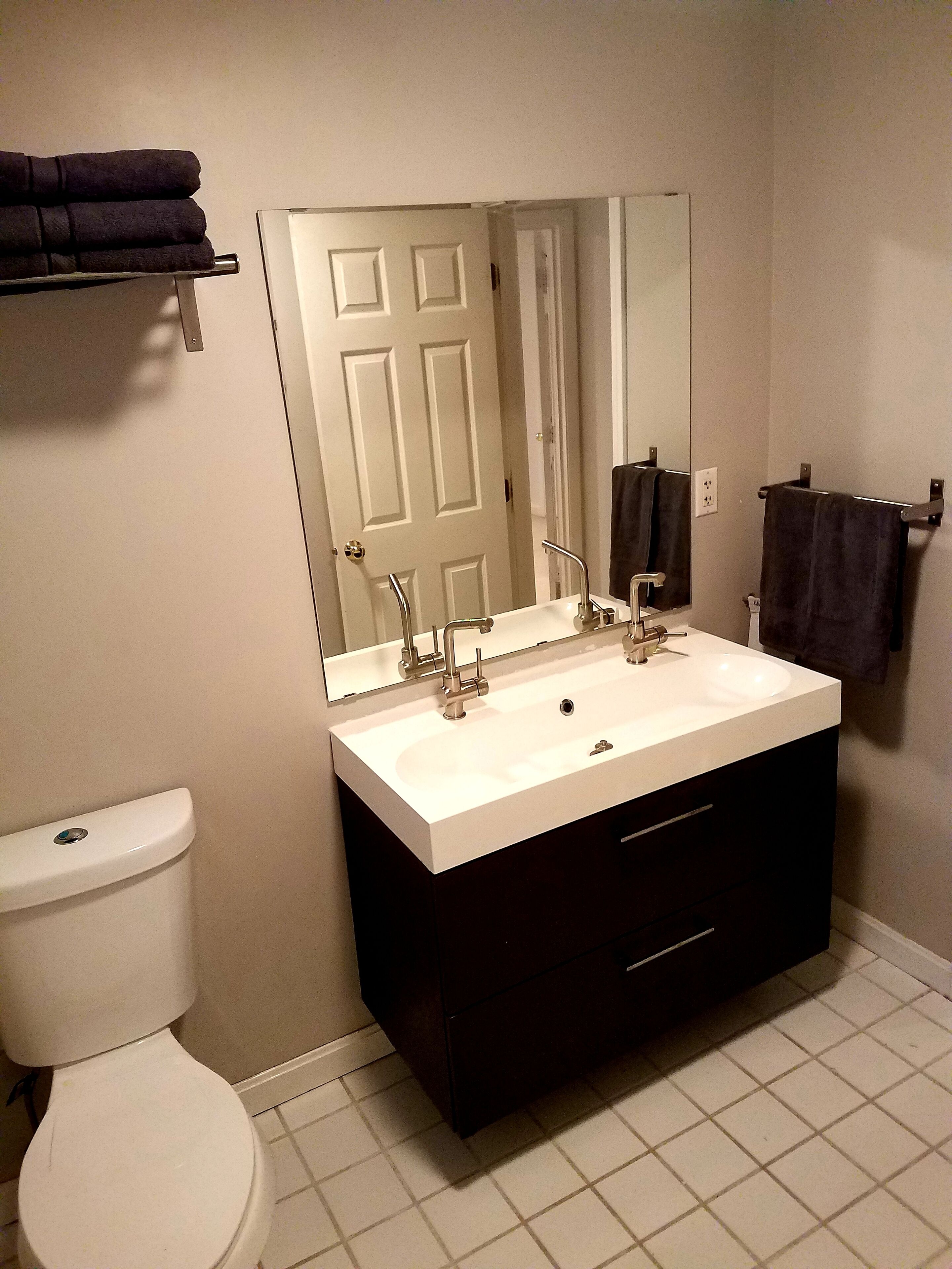 A bathroom with a white toilet, a double sink vanity, and a mirror above the sink.
