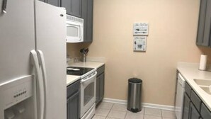 Une cuisine compacte équipée d’un réfrigérateur, d’un four à micro-ondes, d’une cuisinière, d’un évier et d’une poubelle.