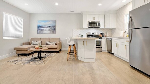 A modern kitchen with white cabinetry, stainless steel appliances, and a central island. - Top-Rated 2BR Home · 5 Miles to Disneyland (Fullerton)