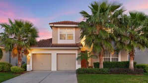 A two-story house with a garage, palm trees, and a well-maintained lawn. - Windsor Orlando Arcade Room, Movie Theater, Pool & Hot Tub, King Bed, Bunk Bed (Kissimmee)