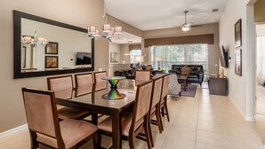 A spacious dining area with a large table and chairs, a chandelier, and a modern kitchen in the background. - Windsor Orlando Arcade Room, Movie Theater, Pool & Hot Tub, King Bed, Bunk Bed (Kissimmee)