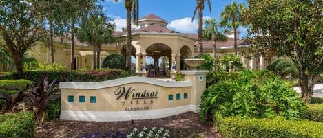 Une entrée aménagée avec un panneau indiquant l’emplacement du club-house de Windsor Hills.