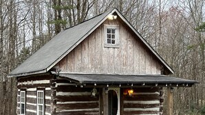 Eine rustikale Holzhütte mit Veranda, einem kleinen Fenster und zwei Holzfässern.