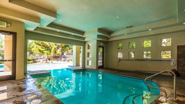 A swimming pool with a clear view of the outdoors, a door labeled "EXIT", and a window with a view of greenery. - Gated Golf Course Community Condo (St. George)