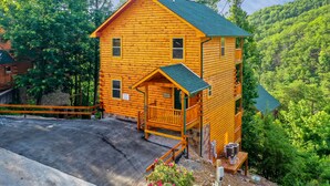 A log cabin with a porch, a small deck, and a stone wall foundation.