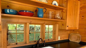A kitchen with wooden cabinets, a black countertop, a sink, and a window with a view of greenery.