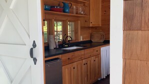 A kitchen with wooden cabinets, a black countertop, and a stainless steel dishwasher.