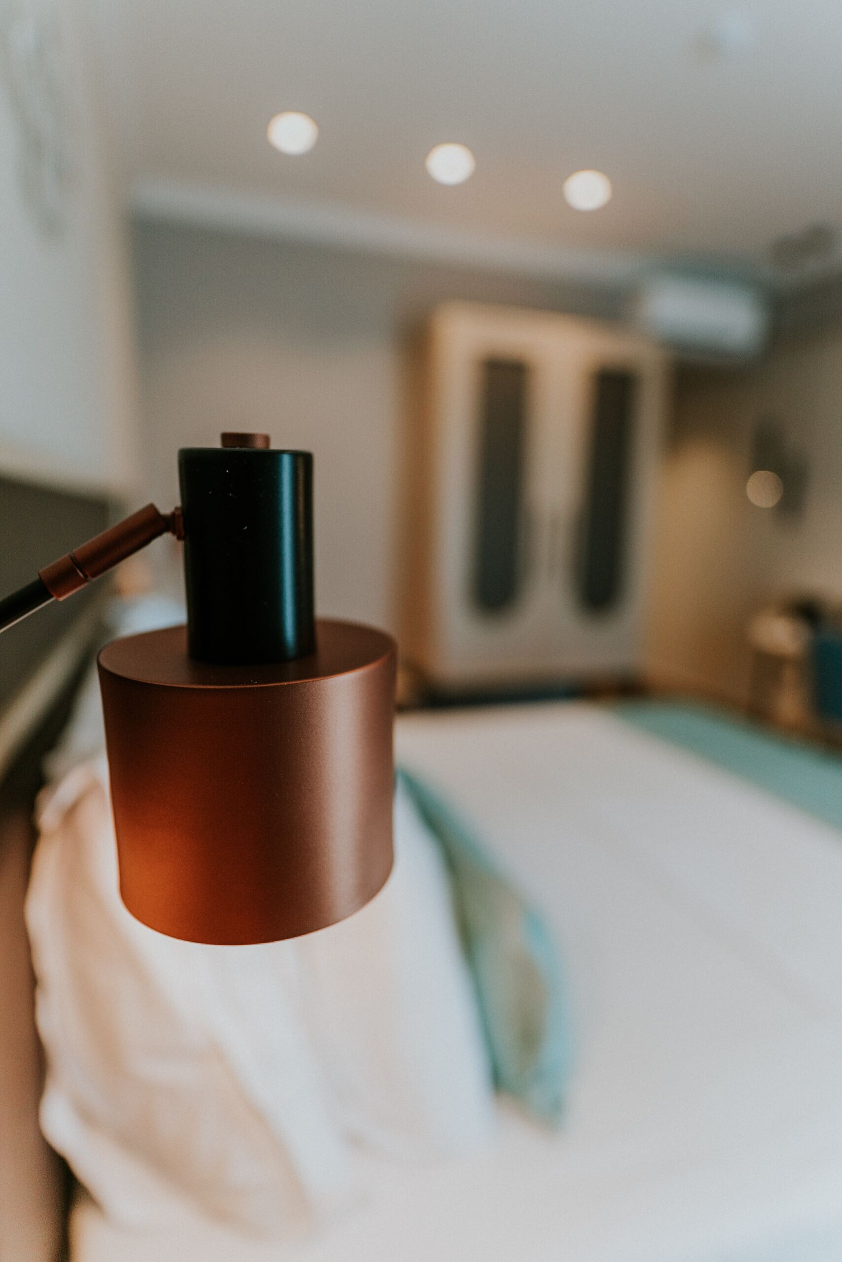 A close-up of a metallic object, possibly a lamp, on a bed with a white pillow and a blue blanket.