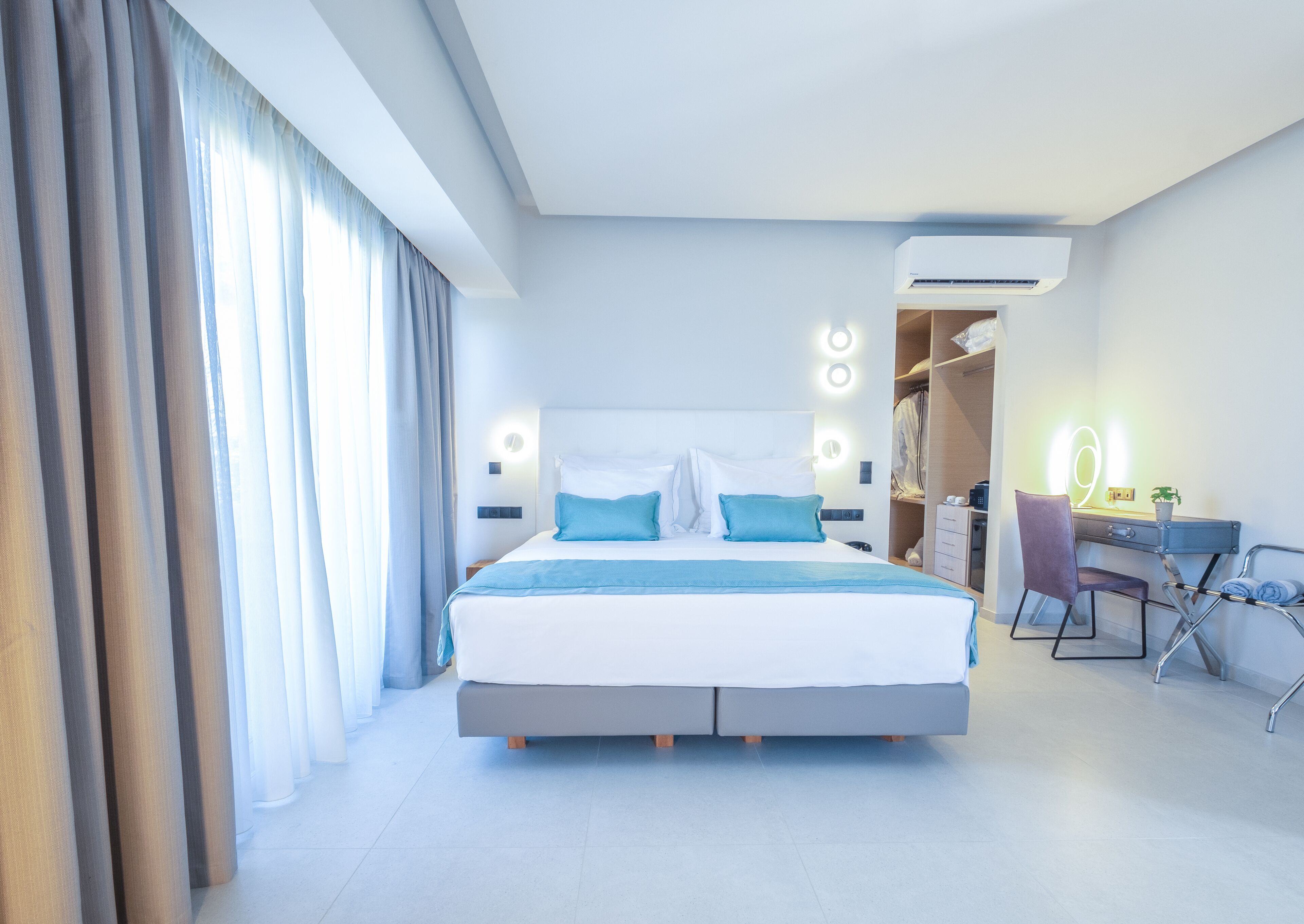 Una habitación de hotel moderna con una cama grande, un escritorio y un armario.