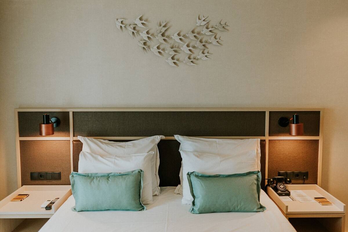 Une chambre d’hôtel avec un grand lit, deux tables de chevet et un élément décoratif mural au-dessus du lit.