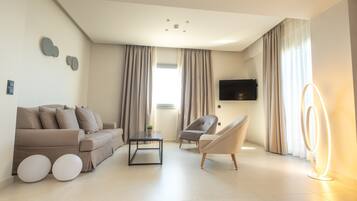 A modern living room with a sofa, armchairs, a coffee table, and a flat-screen TV mounted on the wall.