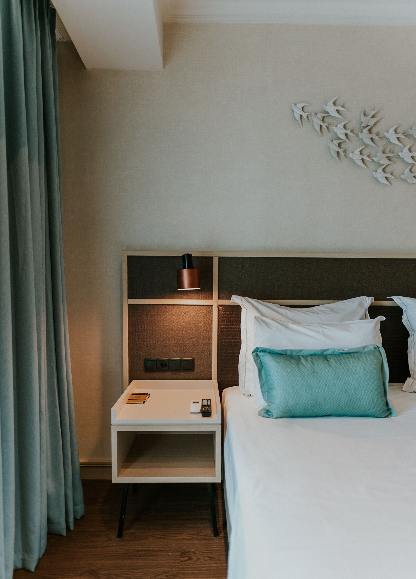 A hotel room with a bed, a nightstand, a lamp, and a wall art piece.
