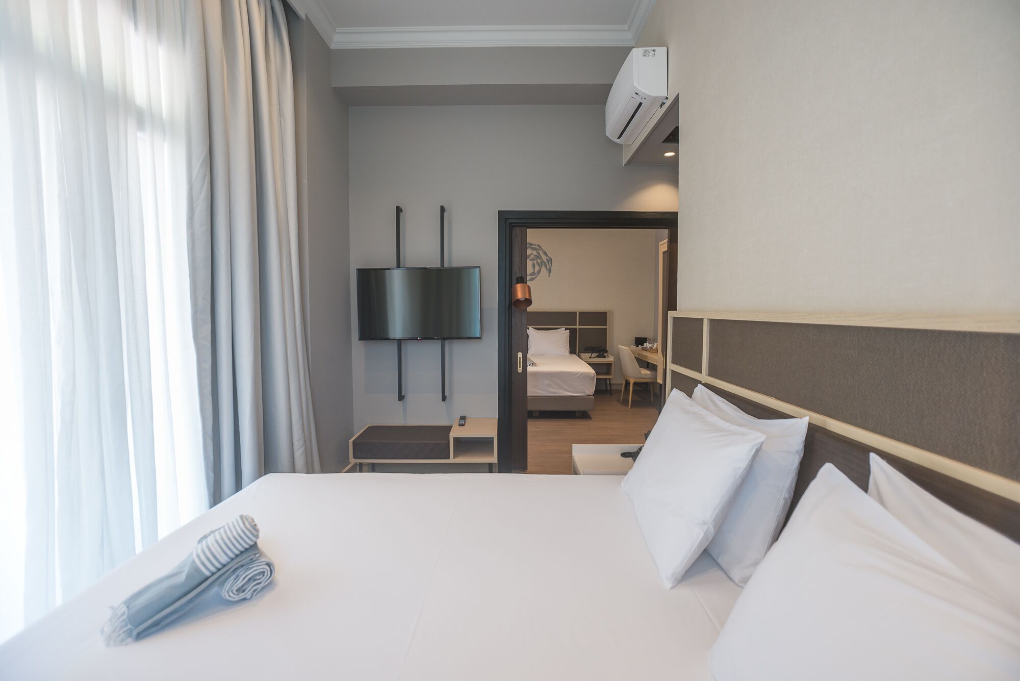 A hotel room with a bed, a TV, a desk, and a chair.