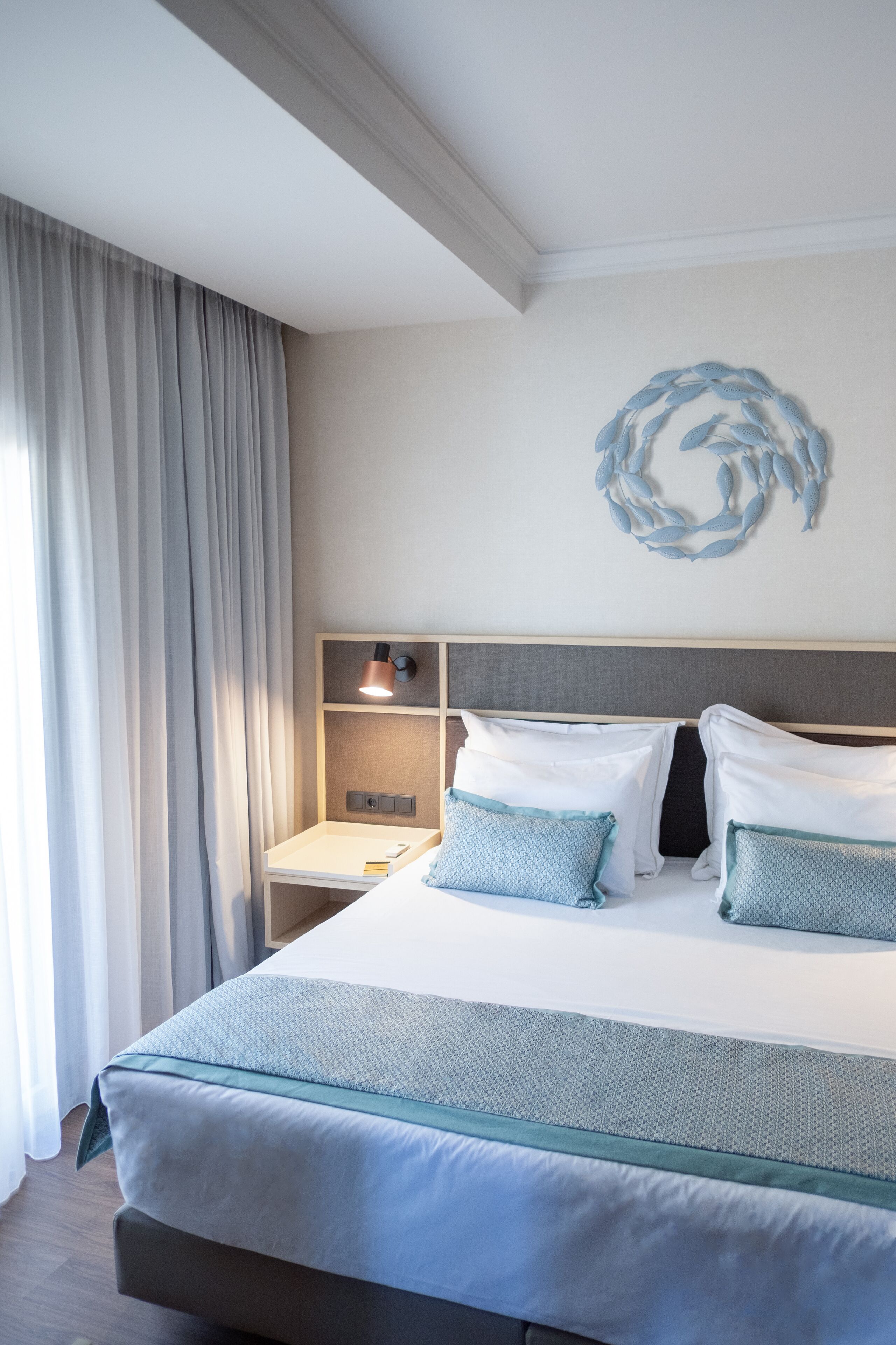 Un letto rifatto con una testiera, un comodino con una lampada e una decorazione a parete.