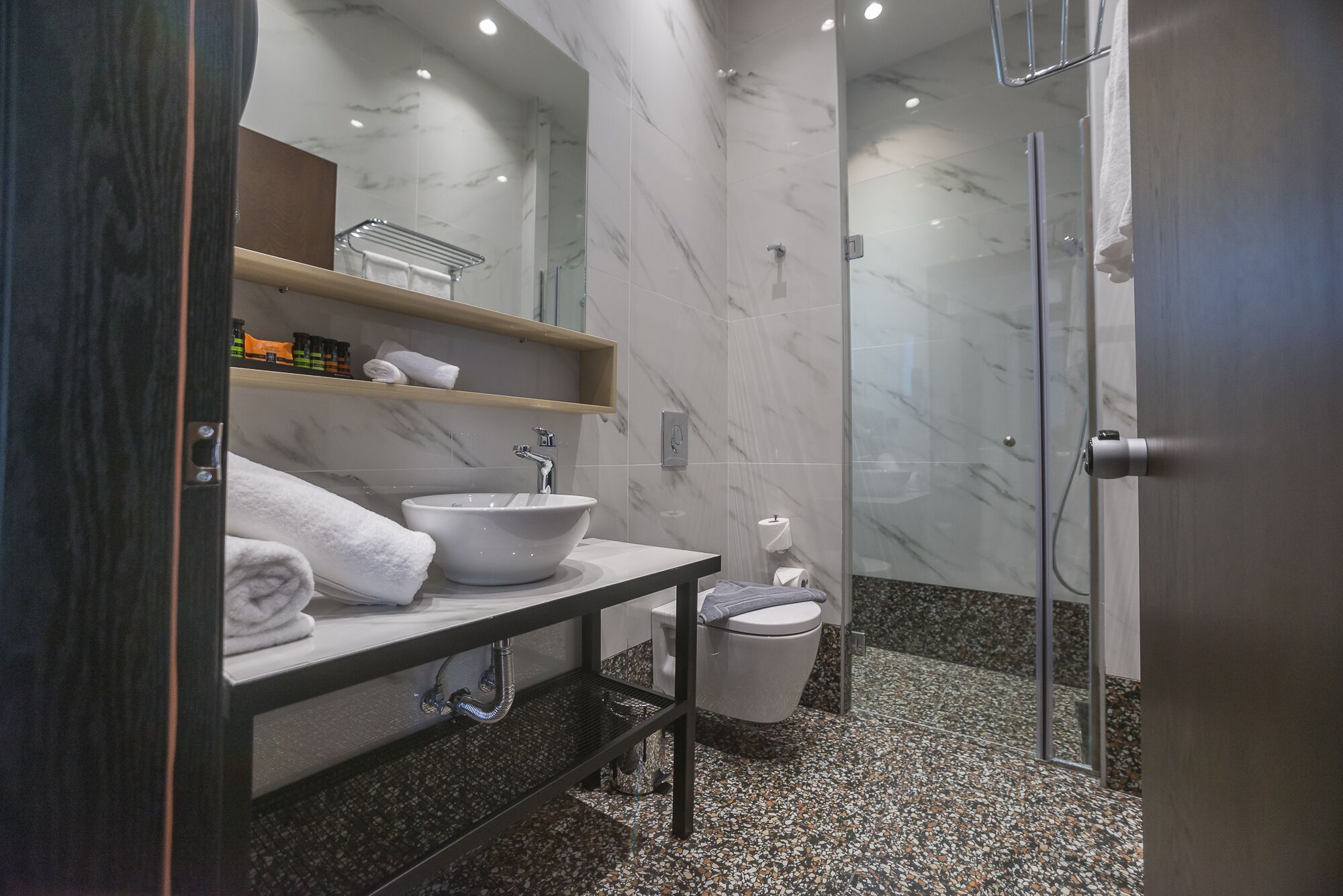 A modern bathroom with a marble sink, a toilet, and a shower.