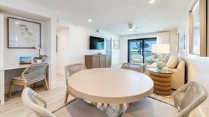 A modern living room with a round table, wicker chairs, a sofa, and a TV. - OCEAN'S REACH 3A4: 2-Bdrm, Top Floor/Corner Unit, Stunning Views! (Sanibel Island)