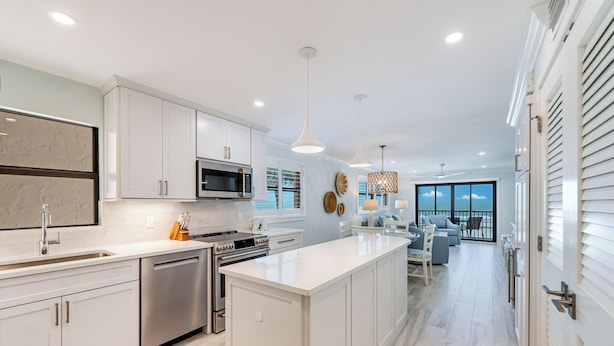 A modern kitchen with white cabinetry, stainless steel appliances, and a large island. - OCEAN'S REACH 2D2: 2-Bdrm, Corner/Gulf-Front View, All Amenities Open! (Sanibel Island)