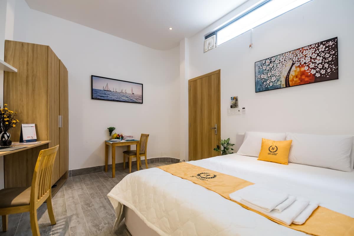 Ein Hotelzimmer mit einem Bett, einem Schreibtisch, einem Sessel und einem kleinen Tisch mit einer Pflanze.