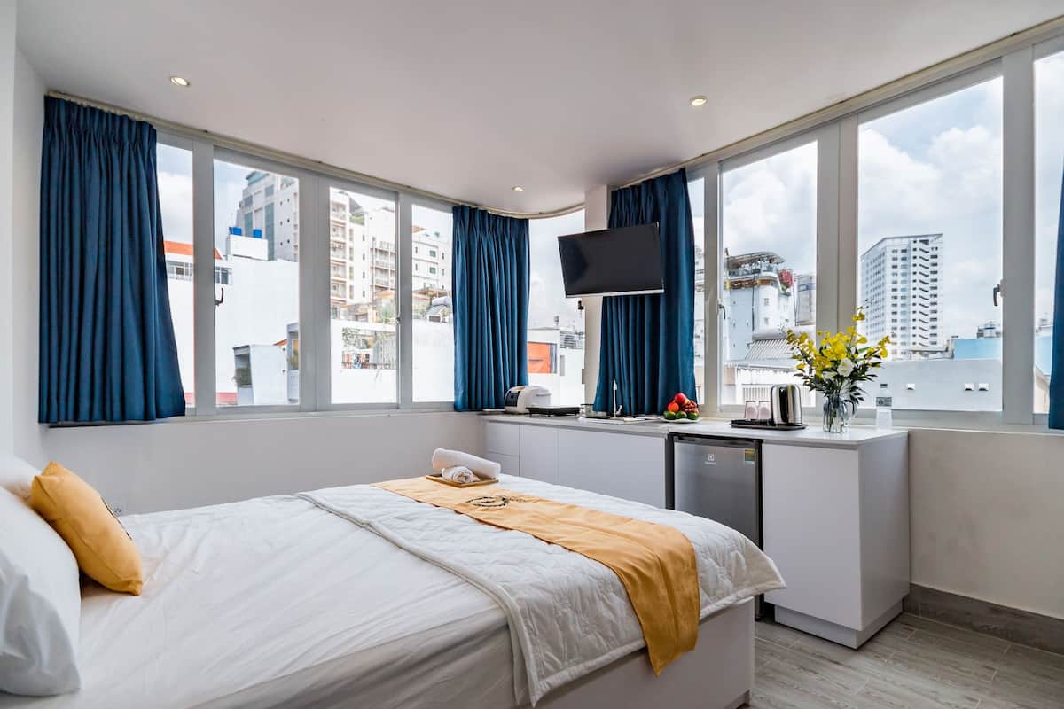 Ein Hotelzimmer mit Bett, Schreibtisch, Fernseher und Blick auf die Stadt.
