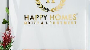 A white wall with a logo and text for Happy Homes Hotel & Apartment. - HAPPYHOMES 102 Luxury Bui Vien Apartment (Ho Chi Minh City)