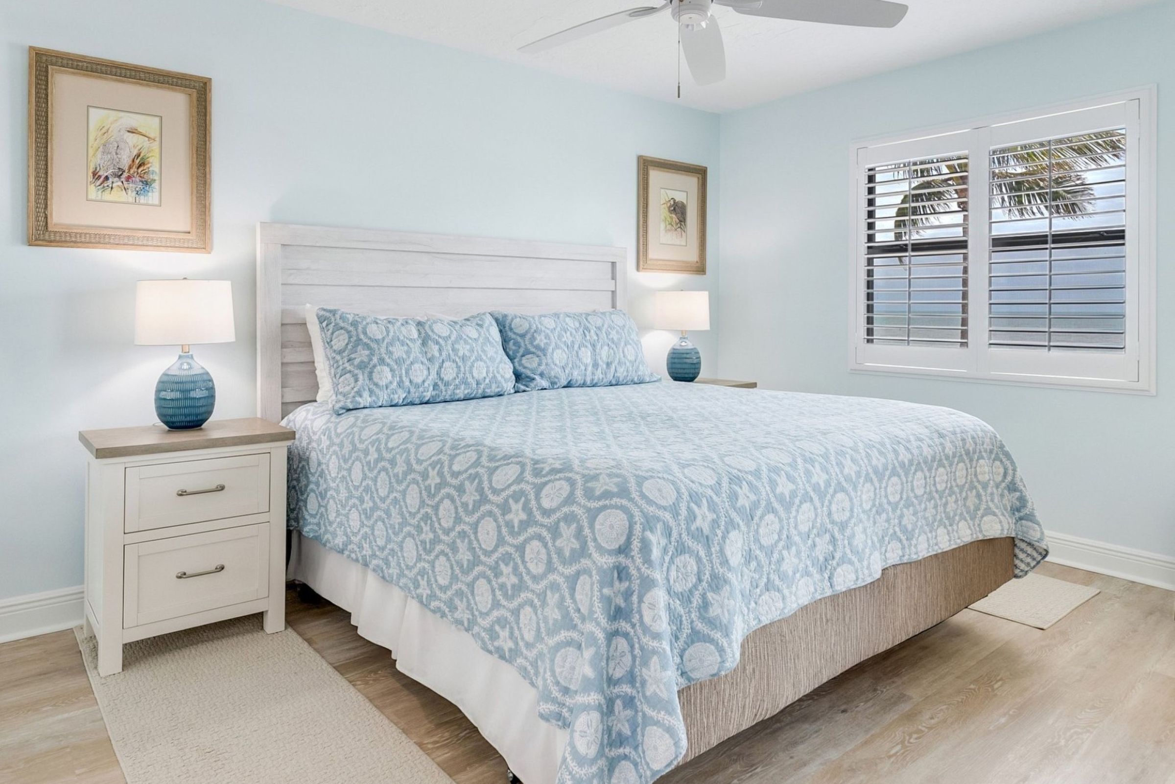 A bedroom with a bed, nightstands, a ceiling fan, and a window with blinds.