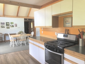 Enjoy cooking in this well-equipped kitchen with a central island, stainless steel stove, and dining area.