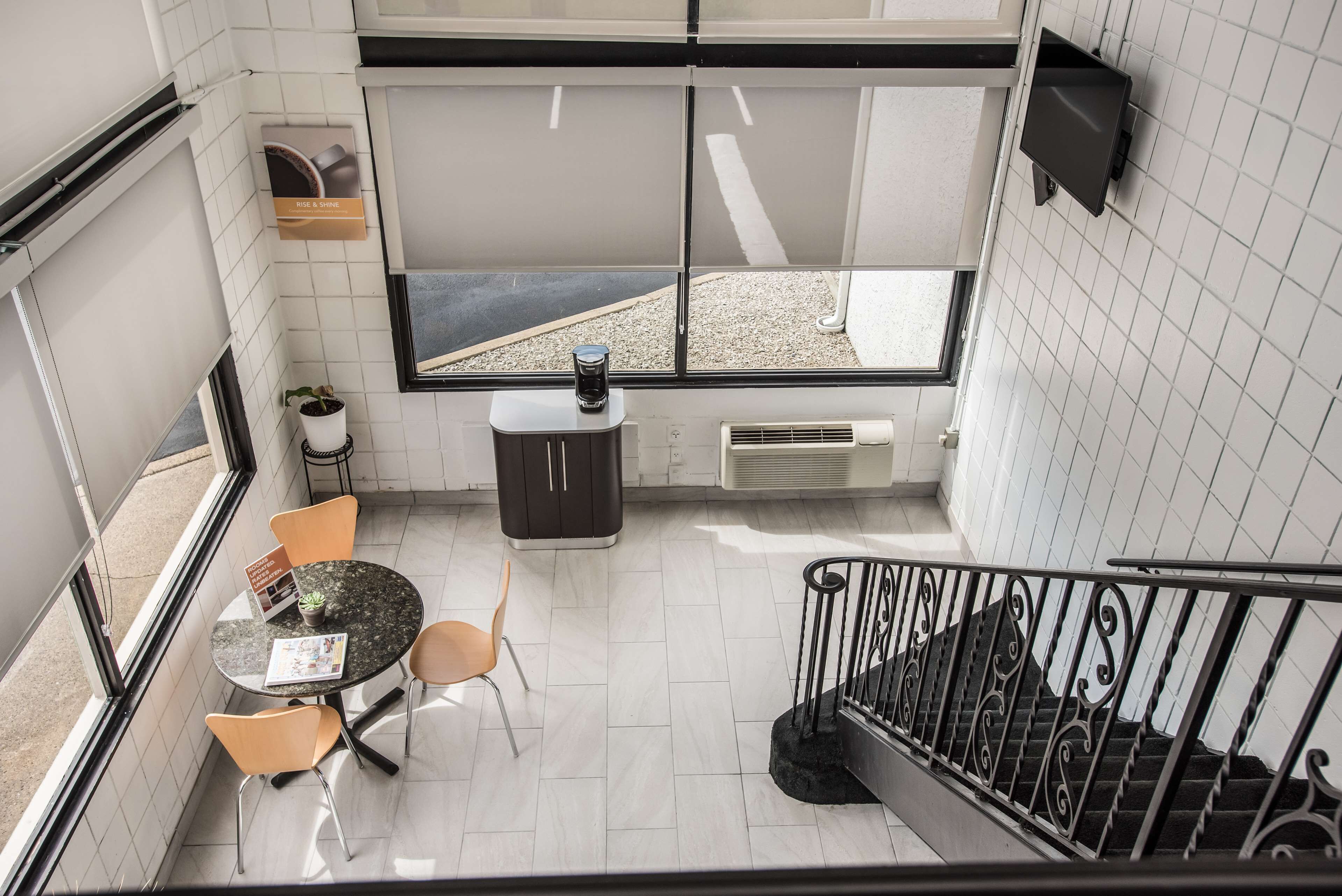 A modern interior with a dining area, a staircase, and a view through large windows.