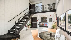 A hotel lobby with a staircase, a reception desk, and seating area.