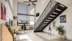 A spacious lobby with a black staircase, large windows, and a view of the outside.