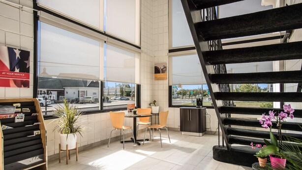 A modern interior with a staircase, a table with chairs, and a potted plant.