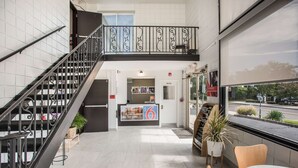 A hotel lobby with a staircase, a reception desk, and a view of the street.