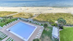 Ein Strandhotel mit Schwimmbad, Liegestühlen und Meerblick.