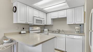 A kitchen with white cabinets, a microwave, a dishwasher, and a coffee maker.