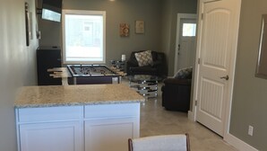 A kitchen with a central island, a dining table with placemats, and a living area with a couch and a TV. - Best of Padre Island! Less than 1.5 miles to Luby Beach! (Corpus Christi)